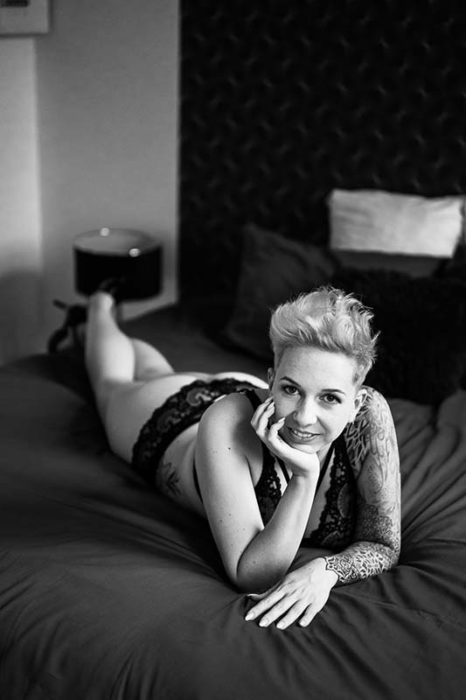 photo noir et blanc d'une femme qui pose sur son lit sur le ventre pour une photographe boudoir à Montreal
