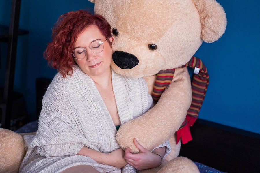 femme pendant sa séance boudoir lovée contre son ours en peluche géant